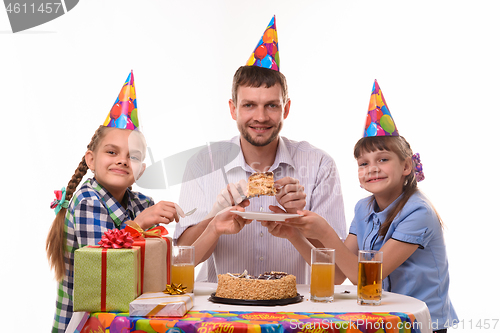 Image of Dad puts the birthday cake on the plates for children