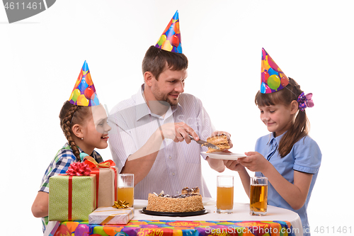 Image of Dad puts his first piece of birthday cake on a plate for his daughter