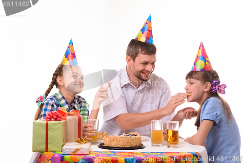 Image of Dad fun stuffing a piece of cake in his daughter\'s mouth