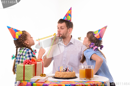 Image of Children and dad joyfully blow whistles to the horns at a birthday party