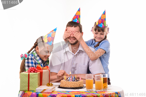 Image of Children prepare a holiday surprise and light candles on a cake