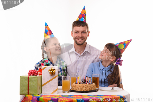 Image of Two girls happily look at dad at the festive table