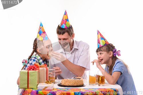 Image of Dad and kids have fun eating cake at the festive table