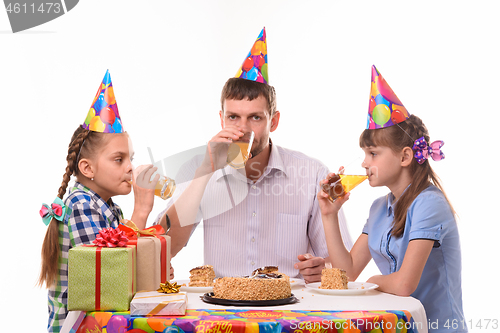Image of Dad and two daughters drink juice at the festive table