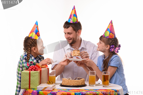 Image of Dad puts a piece of holiday cake on a plate and looks at his daughter