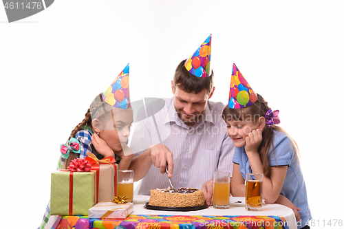 Image of Dad and two daughters cut a birthday cake with a knife