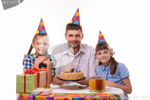 Image of Dad and two daughters with a holiday cake at the table happily look at the frame