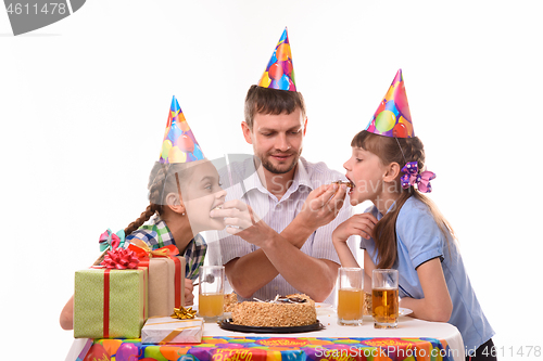 Image of Kids bite pieces of cake from dad\'s hands, having fun celebrating a birthday