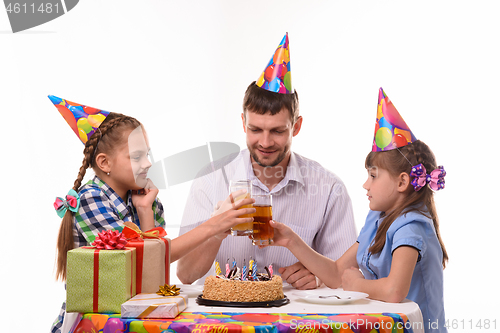 Image of Kids and dad joyfully banging glasses of juice at a birthday party