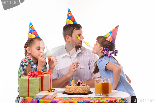 Image of Girl got into the eyes of dad blowing a festive pipe at a birthday party