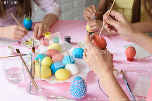 Image of Family decorates chicken eggs on the table for Easter, close-up