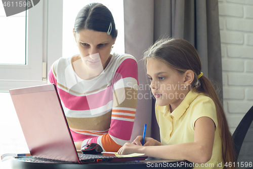 Image of Mom and daughter solve homework using online distance learning