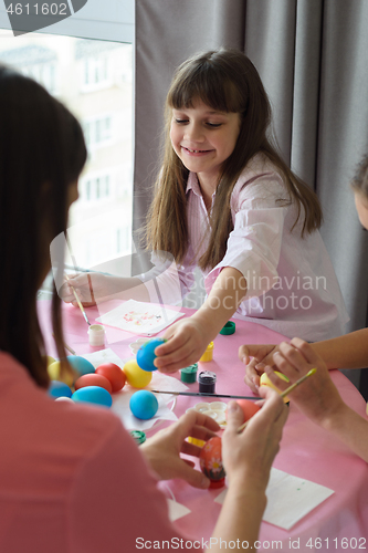 Image of Happy child paints Easter eggs with his family