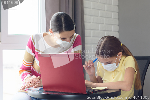 Image of In quarantine, mom helps the girl complete her homework