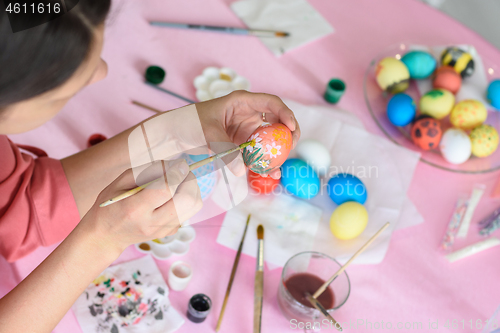 Image of Girl paints chicken eggs for Easter