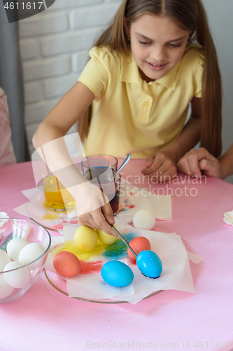 Image of Girl paints Easter eggs in a special solution and puts on a plate