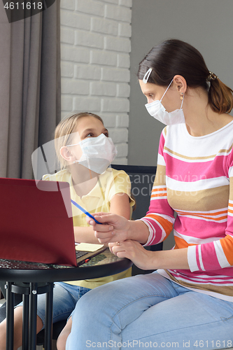 Image of Quarantined family, daughter doing homework, mom helps her