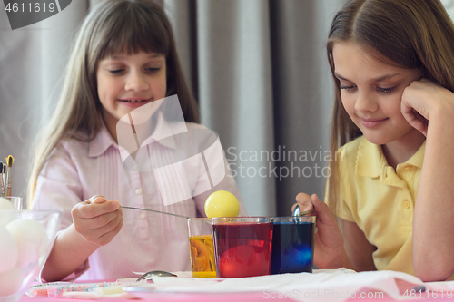 Image of Children paint Easter eggs in glasses with liquid dye