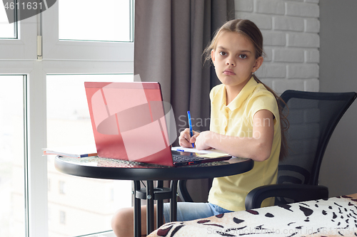 Image of Upset girl doing homework online at home looked in frame