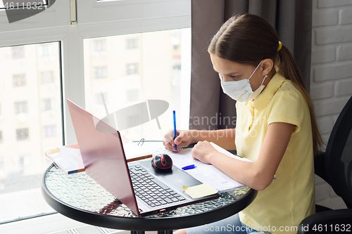 Image of Girl in medical mask does homework using distance learning
