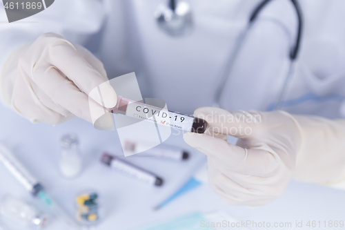 Image of Doctor hands with protective gloves holding COVID 19 Coronavirus