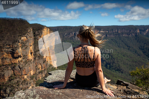 Image of Woman relaxing on a cliff with scenic views