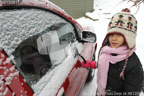 Image of Portrait of a young cute girl looking at the camera romoving sno