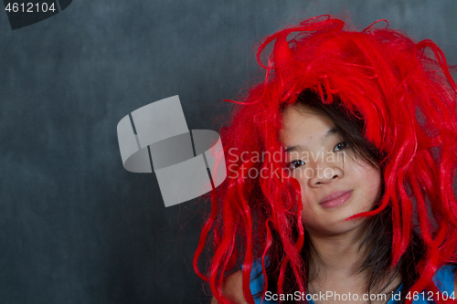 Image of Portrait of a young cute girl with false red hair  looking at th