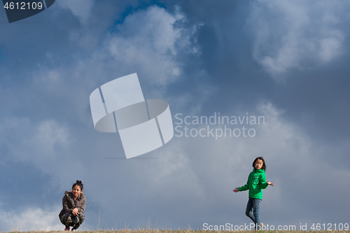 Image of Cute girl running jumping at the on a field in the summer