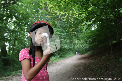 Image of Portrait of a young cute girl looking at the camera eating an ic