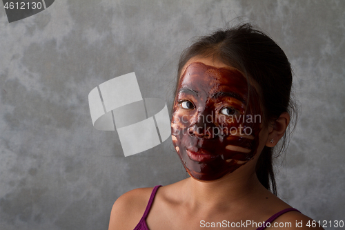 Image of young asian girl having fun with a chocolate mask