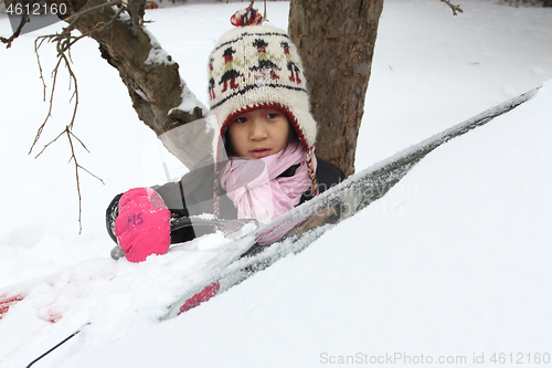 Image of Portrait of a young cute girl looking at the camera romoving sno