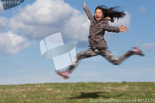 Image of Cute girl running jumping at the on a field in the summer