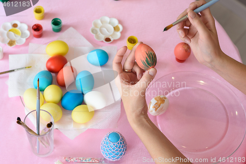 Image of Female hand paints easter eggs, close-up