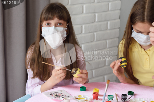 Image of A sick quarantined child paints Easter eggs for the holiday