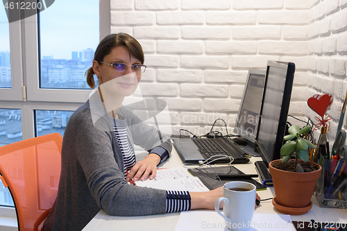 Image of Happy girl working remotely at home looked into the frame