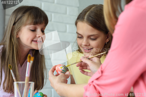 Image of Children watch mom paint Easter eggs beautifully