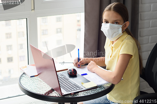 Image of Girl in self-isolation studying online sitting by the window at home