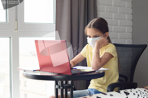 Image of Girl in self-isolation at home sitting at the table and doing homework