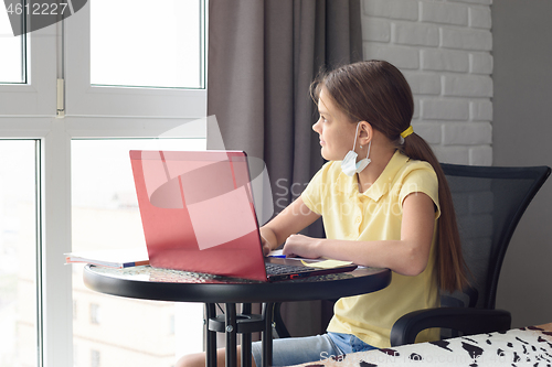 Image of Girl in self-isolation studies at a laptop and looks out the window