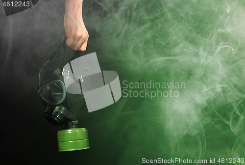 Image of Man in room filled with smoke, holding a vintage gasmask - Green