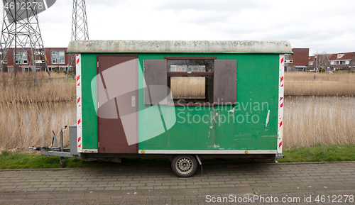 Image of Old green wooden trailer on wheels stands at the side of the roa
