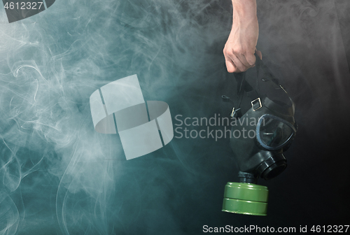 Image of Man in room filled with smoke, holding a vintage gasmask - Blue 