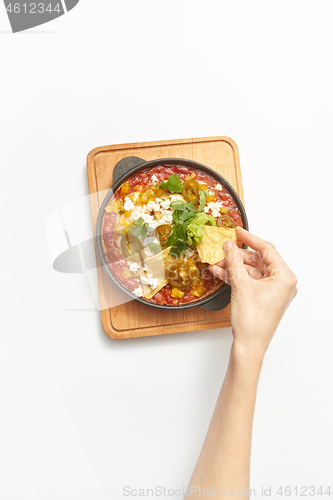 Image of Woman\'s hand takes Shakshouka healthy food from the pan.