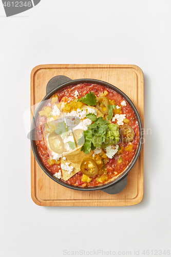 Image of Shakshuka dish with pita bread in a pan on a wooden board.