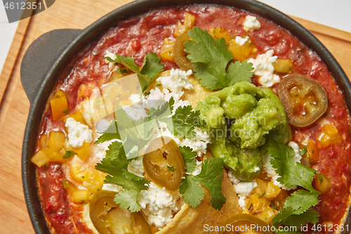 Image of Close up view of Shakshuka dish in a pan with spicy sauce from tomatoes.