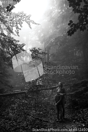 Image of Mother and son in the mystic green foggy forest. The are looking