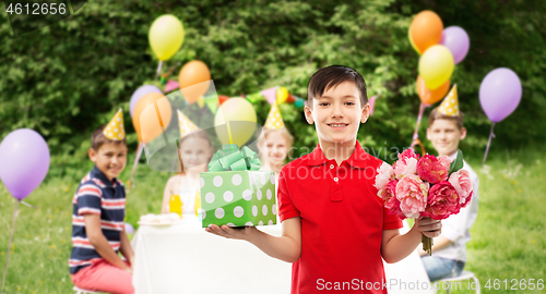 Image of boy with gift box and flowers at birthday party