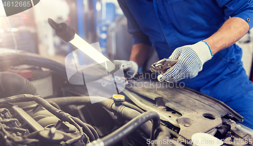 Image of mechanic man with pliers repairing car at workshop