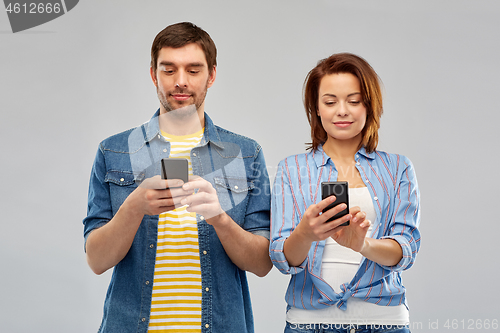 Image of happy couple using smartphones over grey